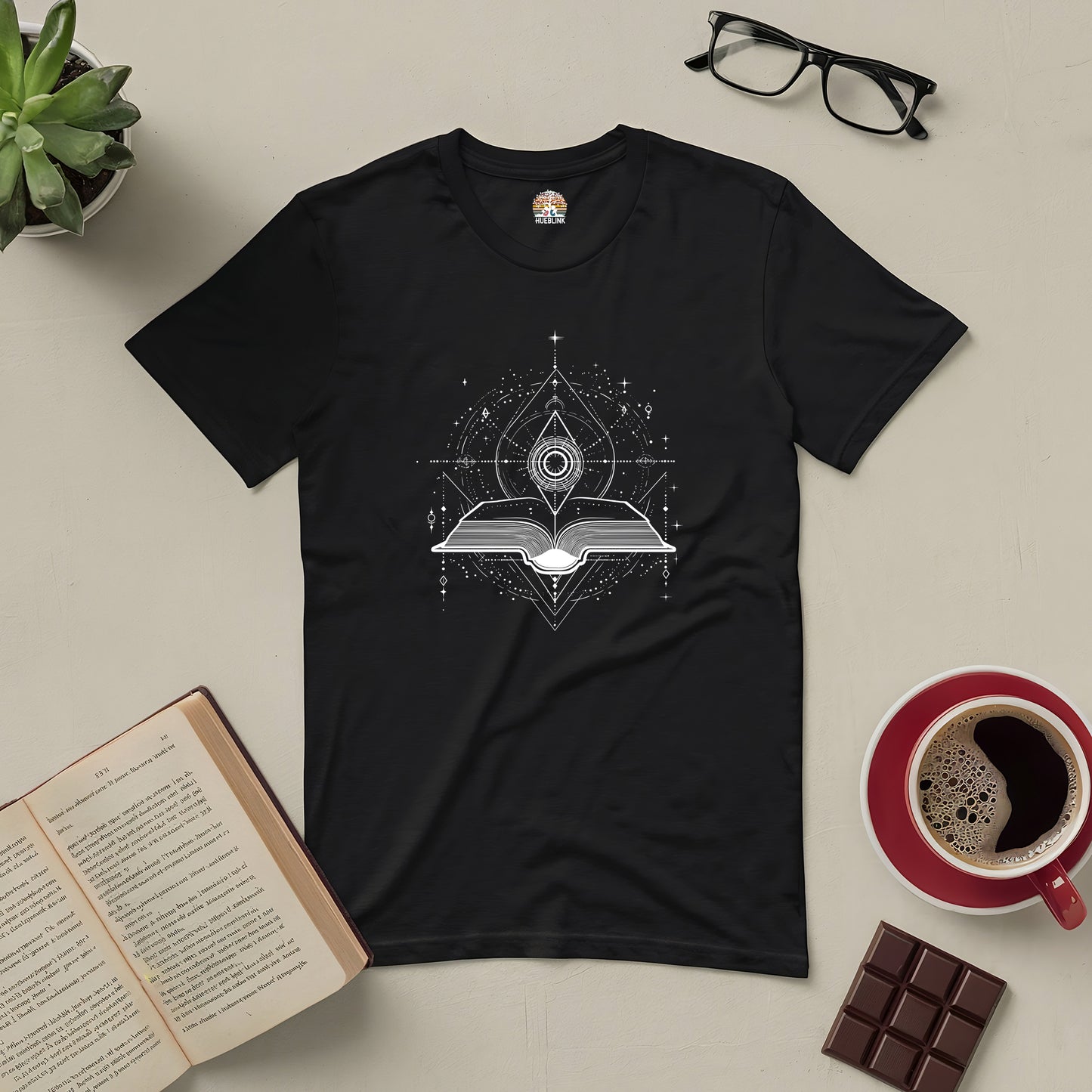 Portal to Knowledge Tee featuring a book design, surrounded by a coffee cup, glasses, open book, and chocolate for curious minds.