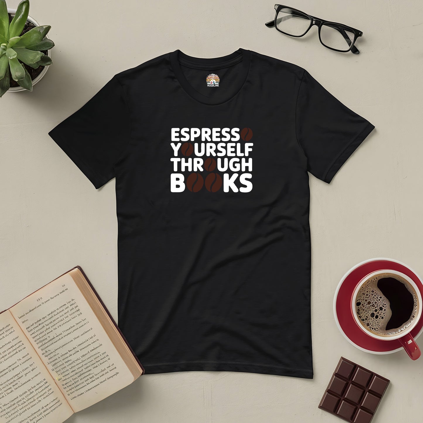 Black t-shirt with "Espresso Yourself Through Books" text, surrounded by coffee, books, glasses, chocolate, and a plant.