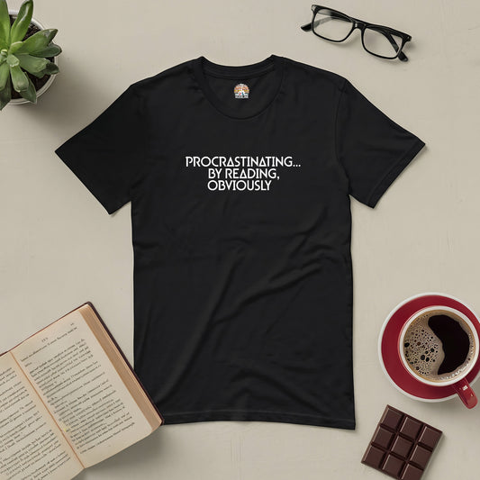 Black tee with "Procrastinating...By Reading, Obviously" text, surrounded by an open book, coffee mug, eyeglasses, and chocolate.