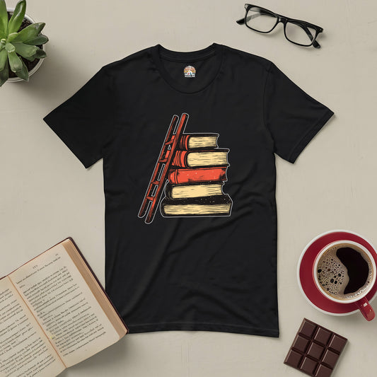 Black t-shirt featuring a ladder leaning against stacked books, symbolizing the journey of knowledge and reading with coffee and glasses nearby.