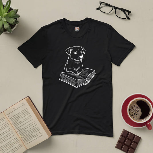 Black "Pawsitive Read" tee with curious pup illustration and book, surrounded by a coffee cup, chocolate, and glasses.