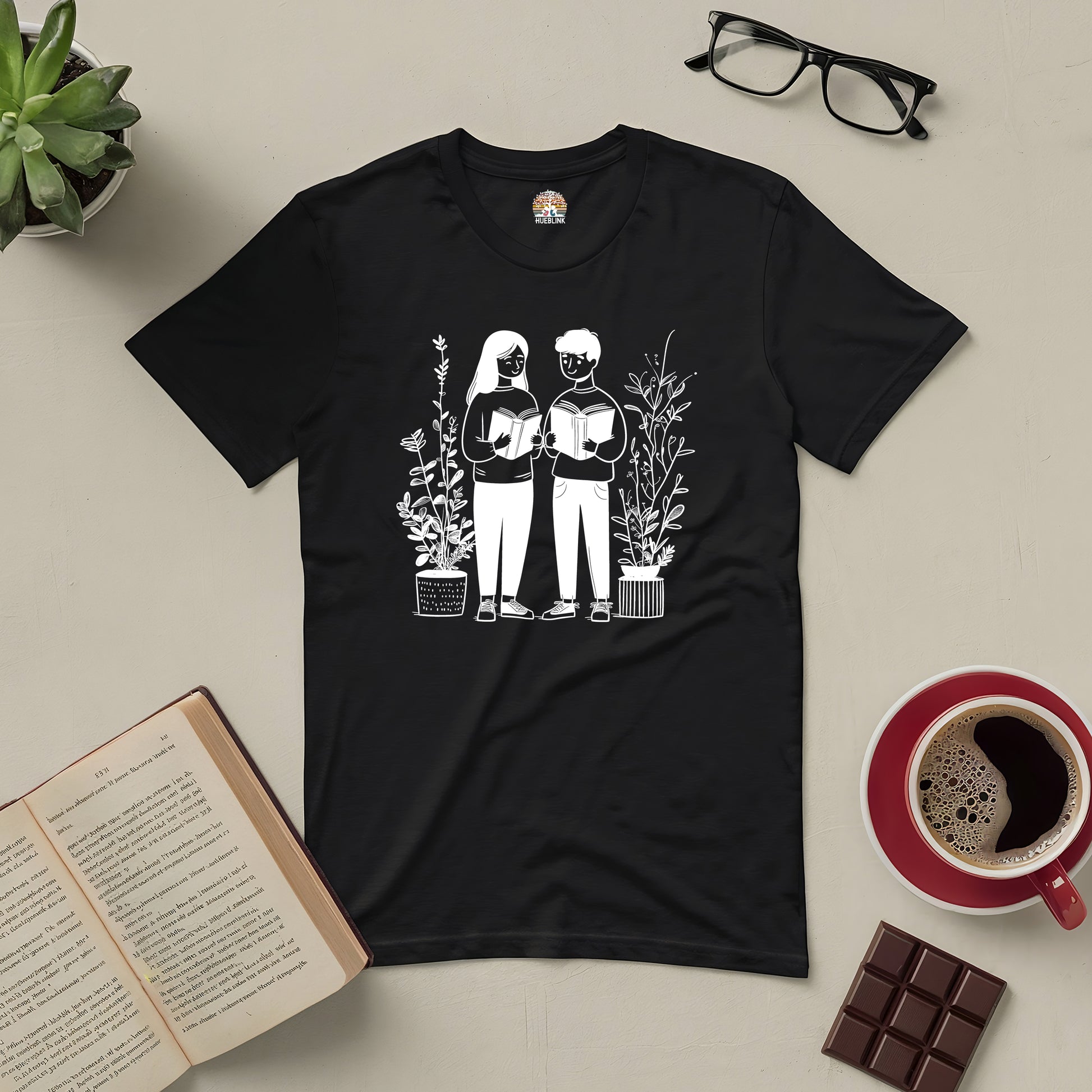 "Bookish Buddies Tee featuring friends reading illustration, perfect for literary duos, surrounded by coffee and books."