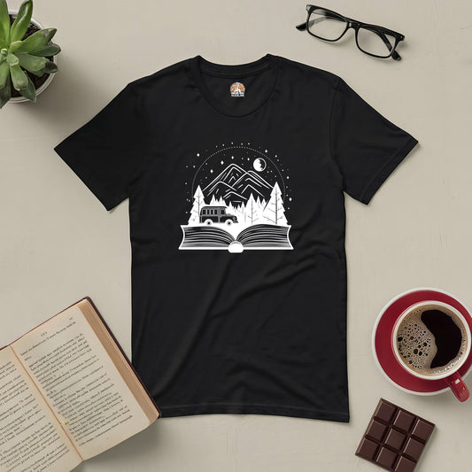 Black t-shirt with open book design, featuring a mountain and night sky, surrounded by a book, glasses, coffee, and chocolate.