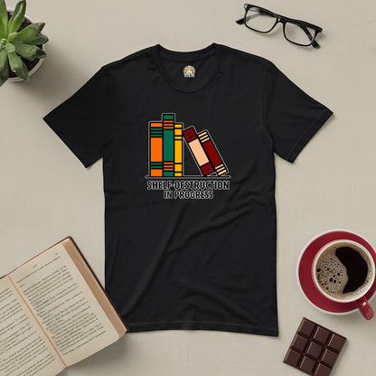 "Shelf-Destruction In Progress Tee with book graphic, perfect for book lovers, displayed with open book, coffee, and chocolate"