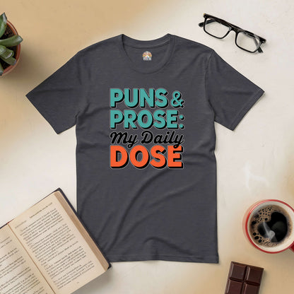 "Puns & Prose: My Daily Dose Tee with humor and literary design on a dark shirt, surrounded by coffee, book, and glasses"