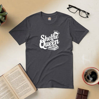 "Shelfie Queen tee with book and crown design, perfect for book lovers, surrounded by an open book, coffee, and glasses."