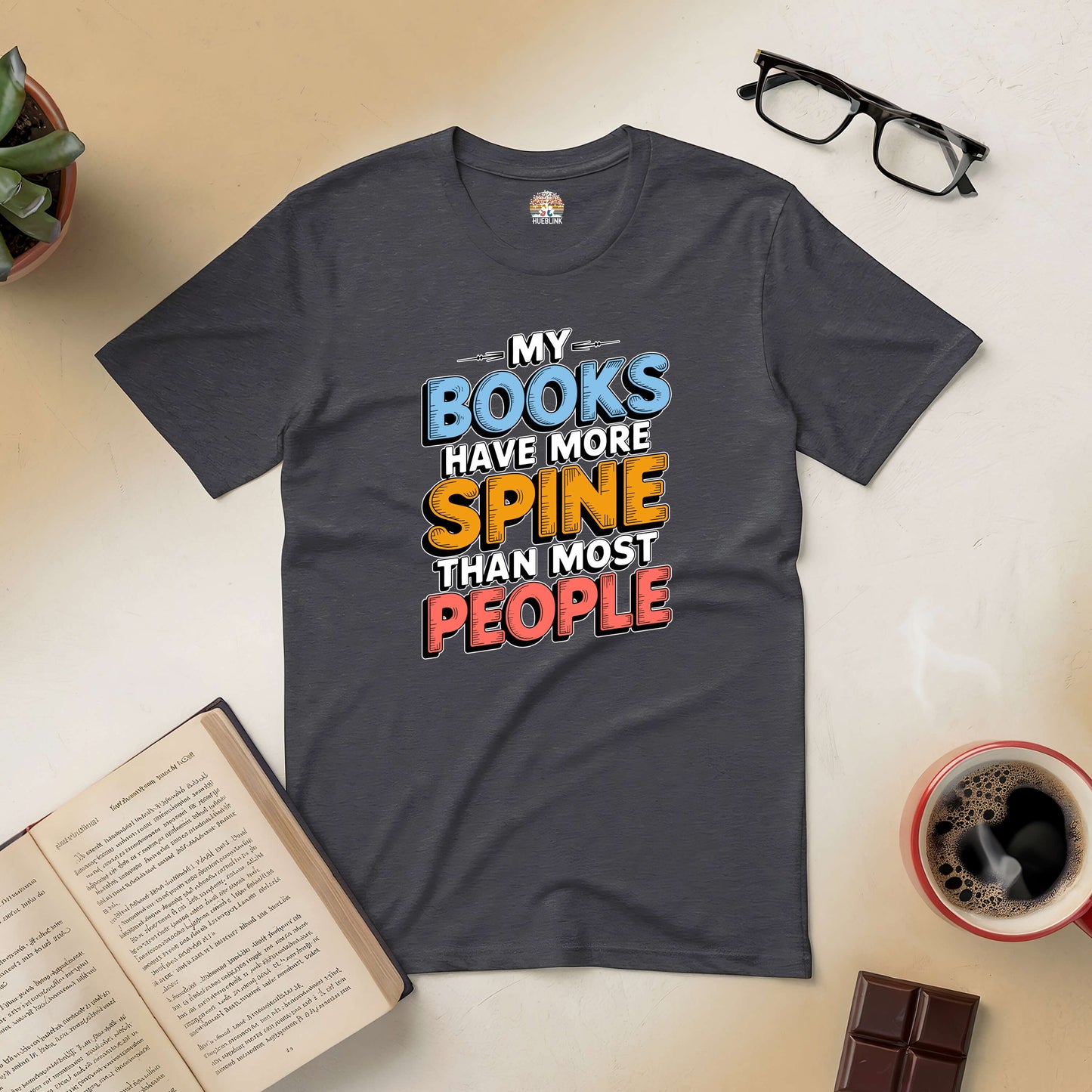 Black t-shirt with the phrase "My Books Have More Spine Than Most People" surrounded by books, glasses, coffee, and chocolate.