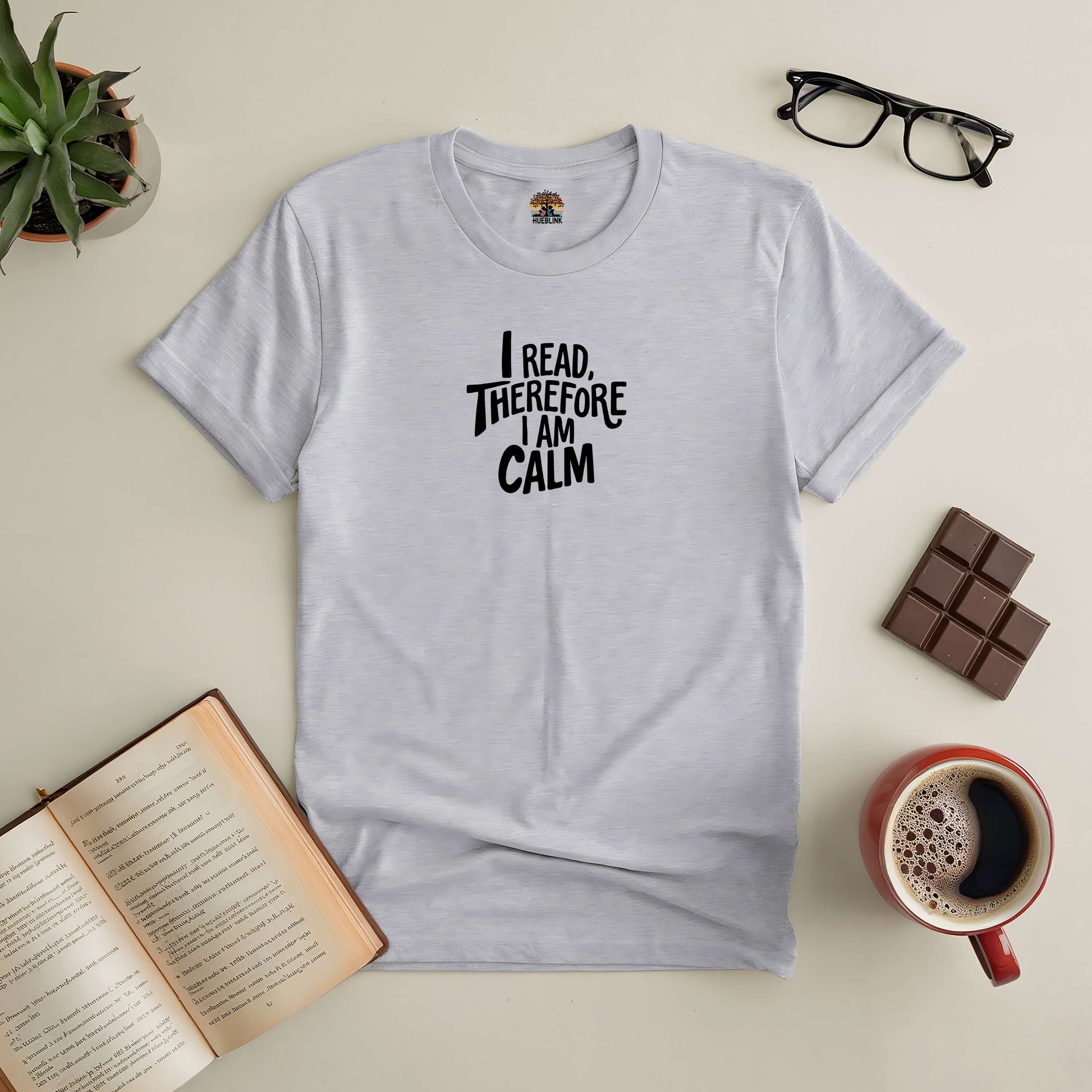 "I Read, Therefore I Am Calm Tee with open book, coffee, chocolate bar, and glasses, ideal for serene readers and book lovers"