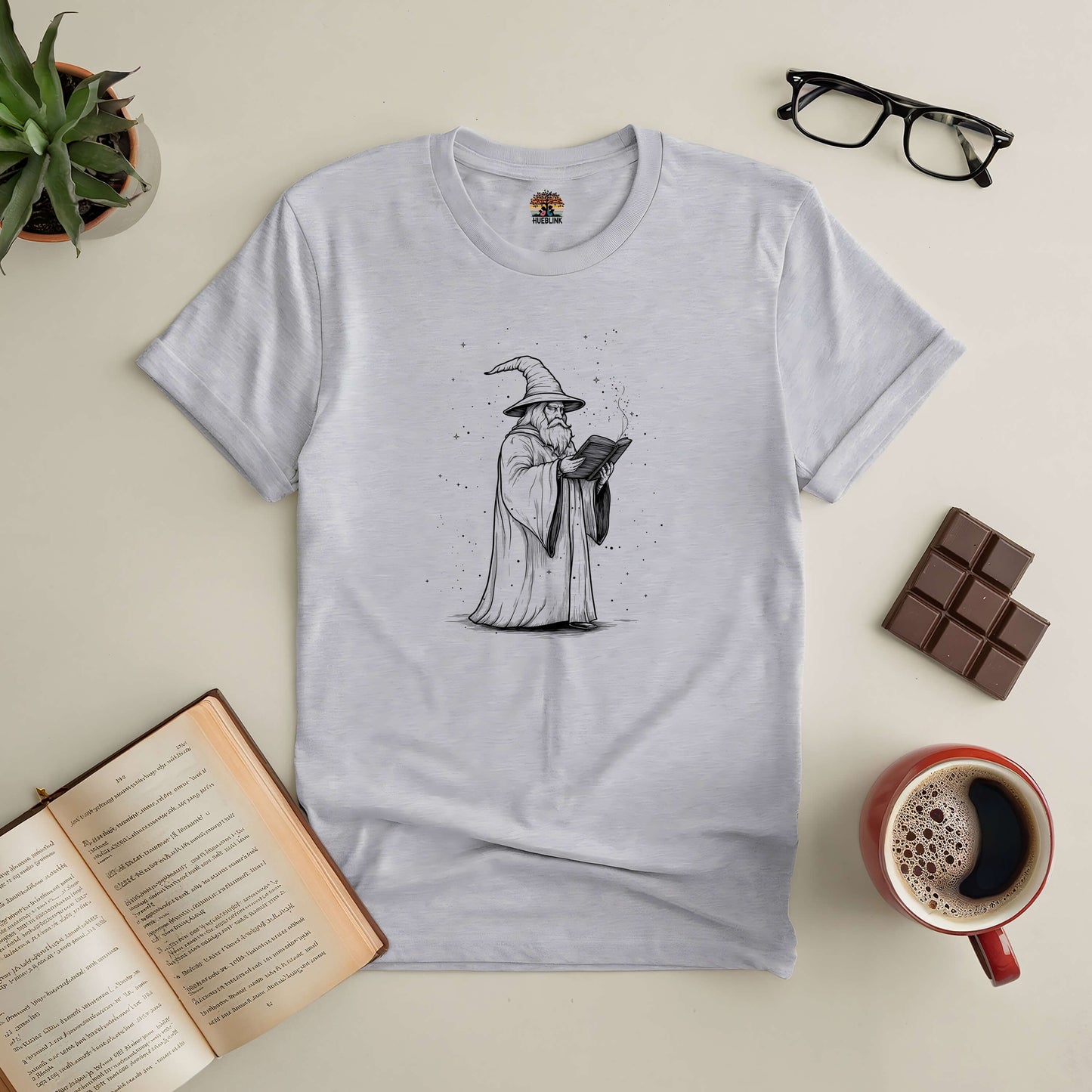 "The Wizard's Grimoire Tee with mystical wizard design, perfect for book lovers and fantasy enthusiasts, displayed on a flat lay"