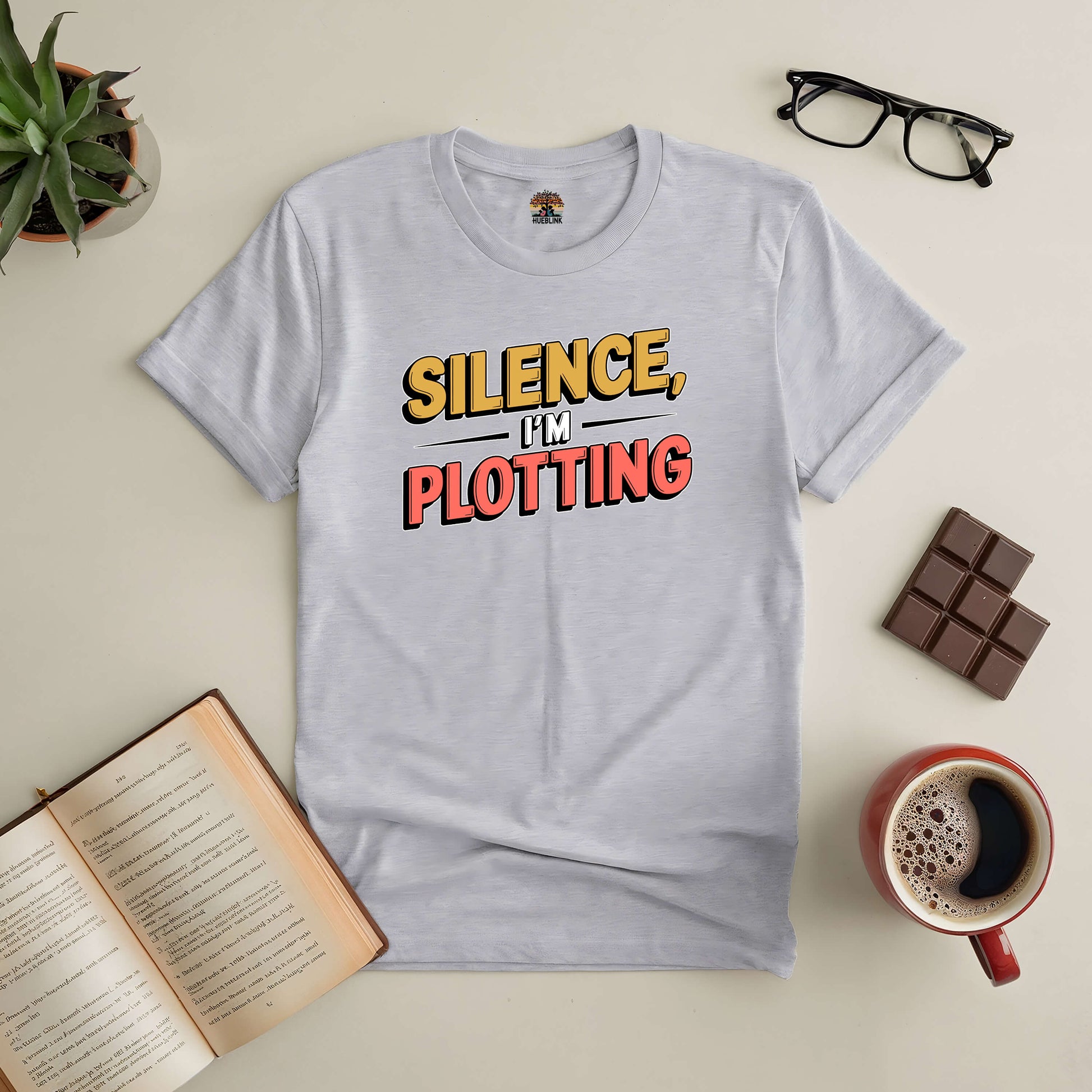 "Silence, I'm Plotting Tee for book lovers with creative design, perfect for writers deep in thought, surrounded by coffee and books"