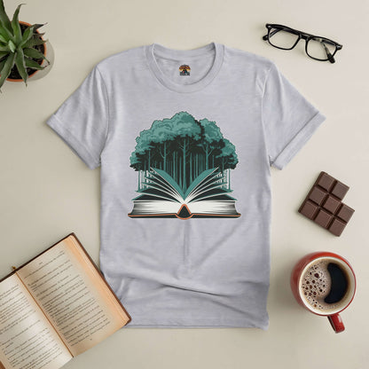 Gray T-shirt with forest and open book design, symbolizing the "Rooted in Story" theme, placed on a table with books, glasses, and coffee.