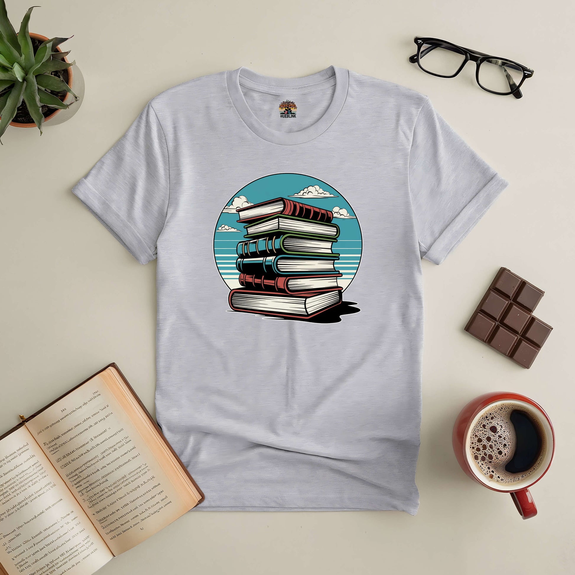 "Silent Knowledge Tee with stack of books against a serene sky, perfect for book lovers and introspective readers."