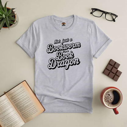 "Not Just a Bookworm, I'm a Book Dragon Tee with open book, glasses, coffee, chocolates, and plant."