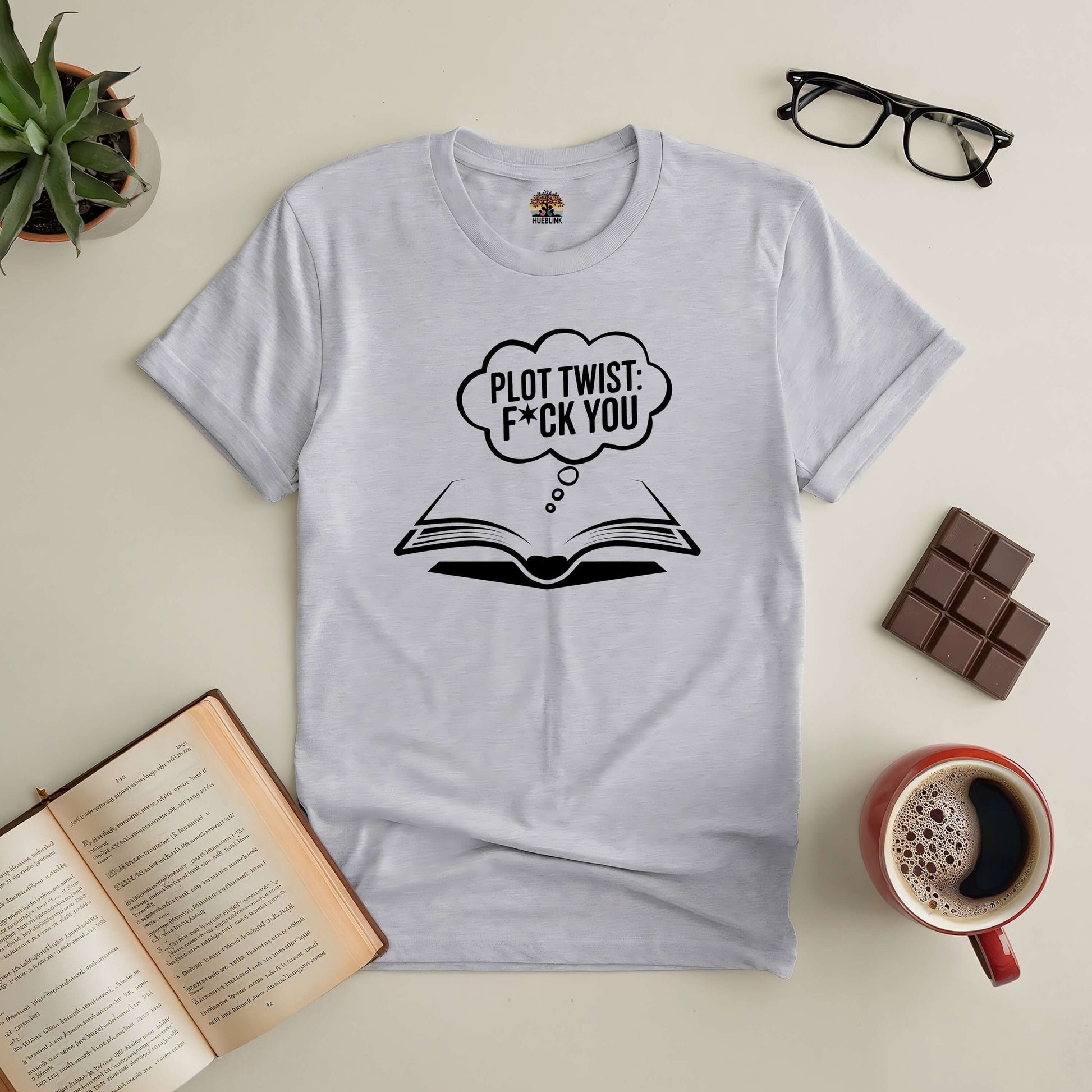 "Plot Twist: F*ck You Tee with book graphic for book lovers, surrounded by coffee, chocolate, and reading glasses"