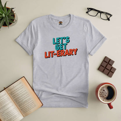 "Let’s Get Lit-erary Tee for book lovers, surrounded by open book, coffee, glasses, chocolate, and plant"