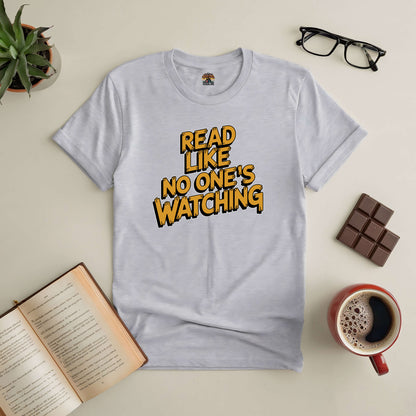 Gray t-shirt with "Read Like No One's Watching" text, surrounded by a mug of coffee, chocolate, open book, and glasses.