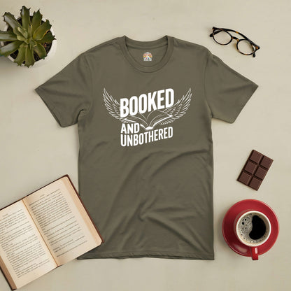 "Booked and Unbothered Tee for book lovers, featuring open book graphic, alongside a cup of coffee, chocolate, and open book on table."