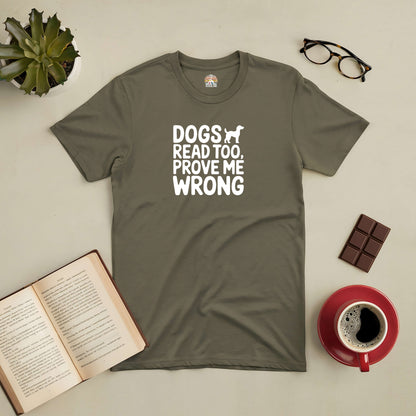 Olive green tee with "Dogs Read Too, Prove Me Wrong" text, paired with a book, coffee, glasses, plant, and chocolate.