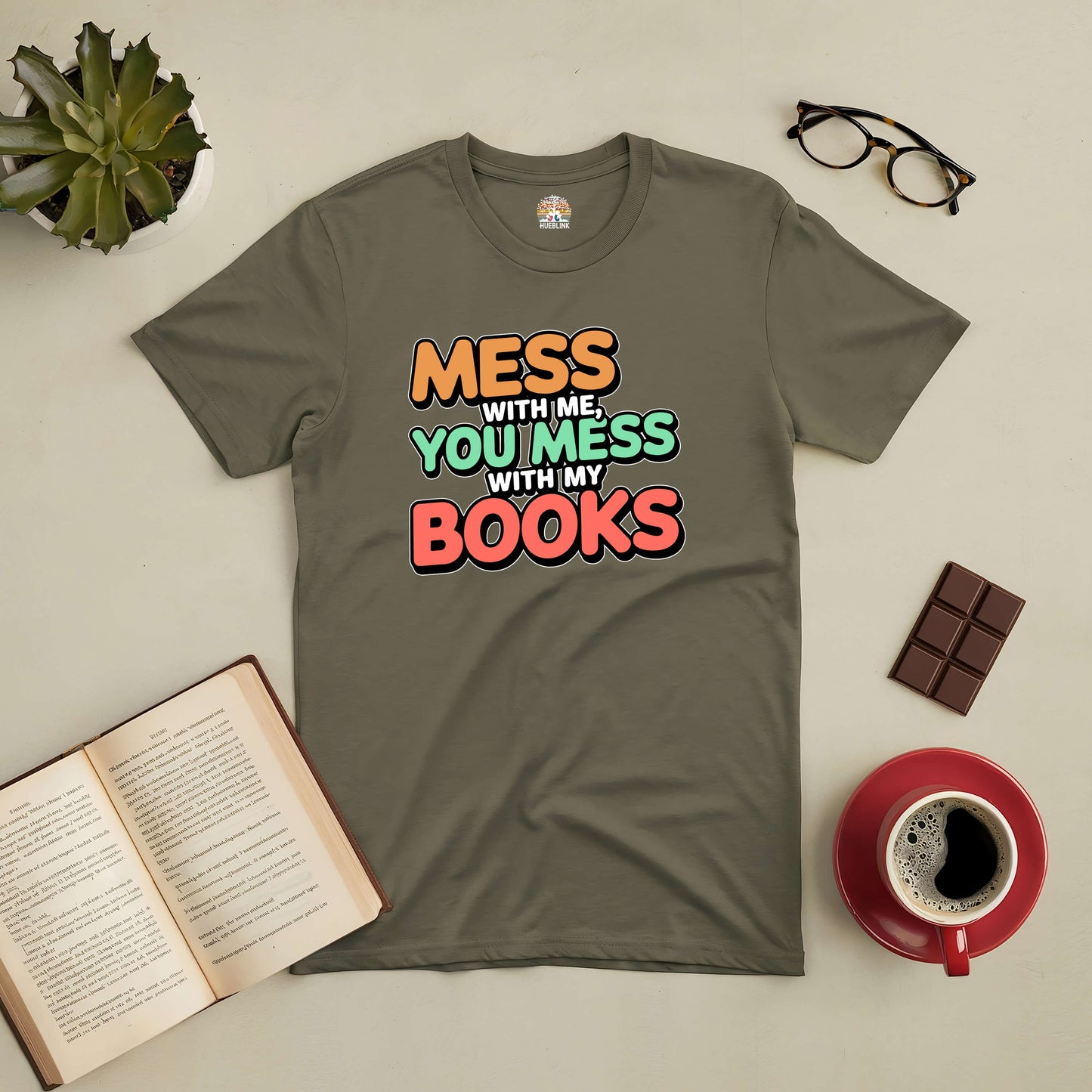 "Mess With Me, You Mess With My Books Tee for book lovers, displayed with coffee, glasses, and an open book on a table."