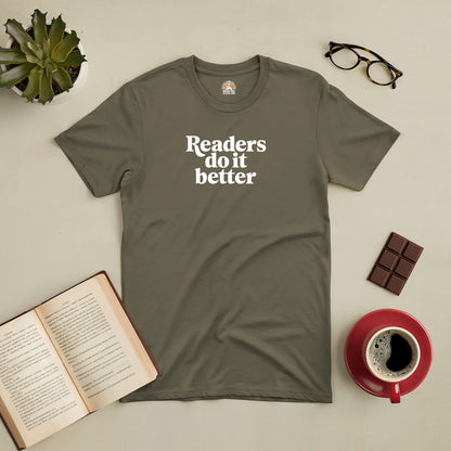 Olive green "Readers Do It Better" tee with open book, eyeglasses, coffee, chocolate, and succulent arrangement.