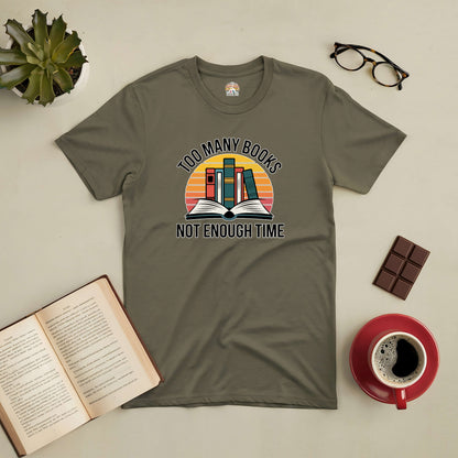 "Too Many Books, Not Enough Time tee for book lovers with open book and sunset design, displayed with coffee, chocolate, and glasses."