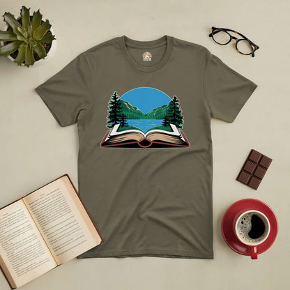 Olive green tee with open book and mountain design, surrounded by a cup of coffee, glasses, chocolate, and an open book.