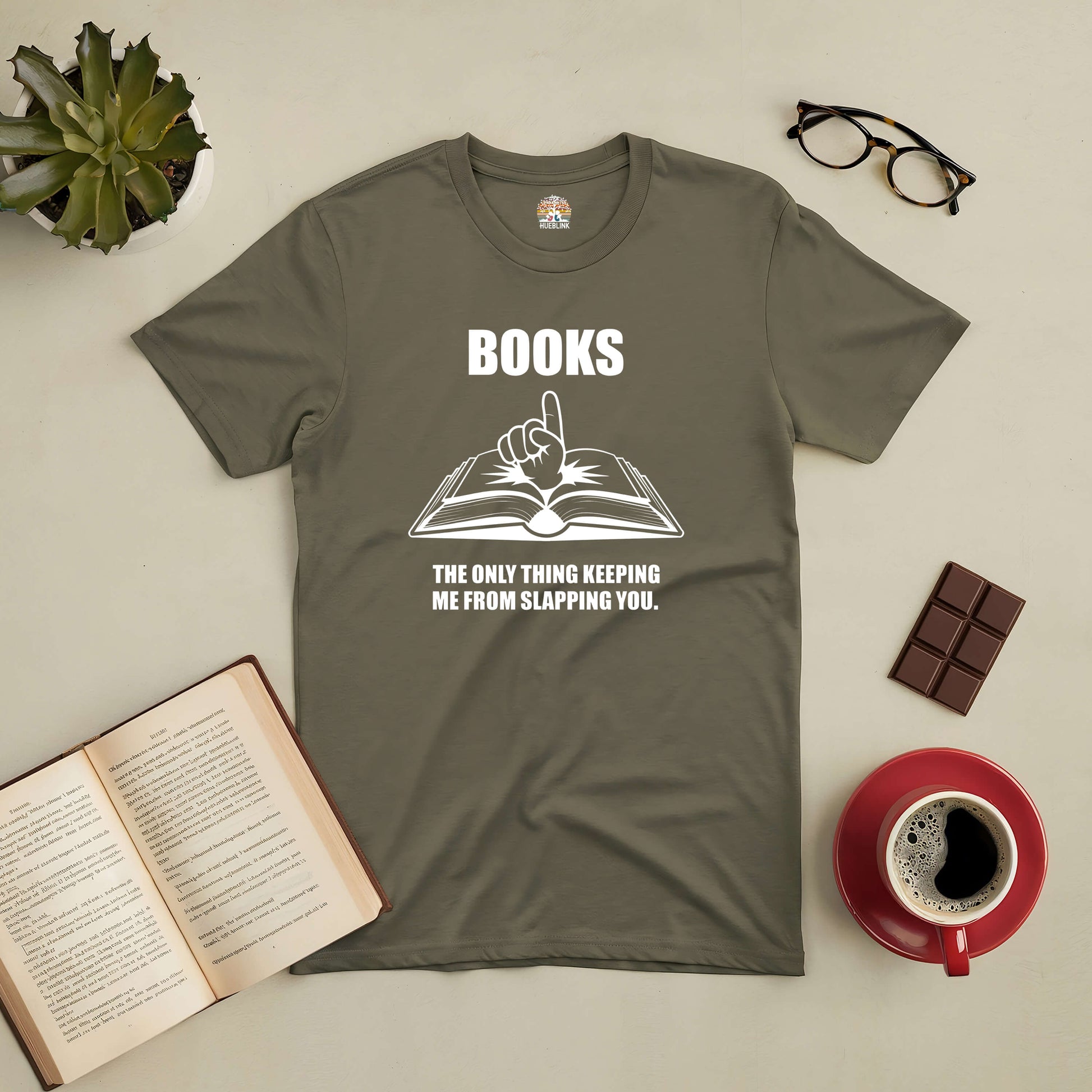 Olive green tee with "Books: The Only Thing Keeping Me from Slapping You" design, surrounded by glasses, open book, and coffee cup.