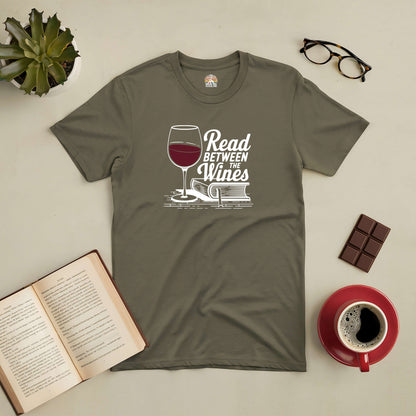 Olive green "Read Between the Wines" tee with book and wine glass graphic, perfect for book lovers and wine enthusiasts.