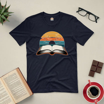 "Narratives in Color Tee with open book and vibrant sky design surrounded by reading essentials"