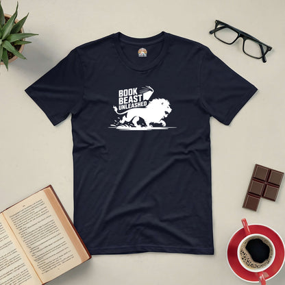 "Book Beast Unleashed Tee with lion design surrounded by book, coffee, and glasses on a flat lay background"