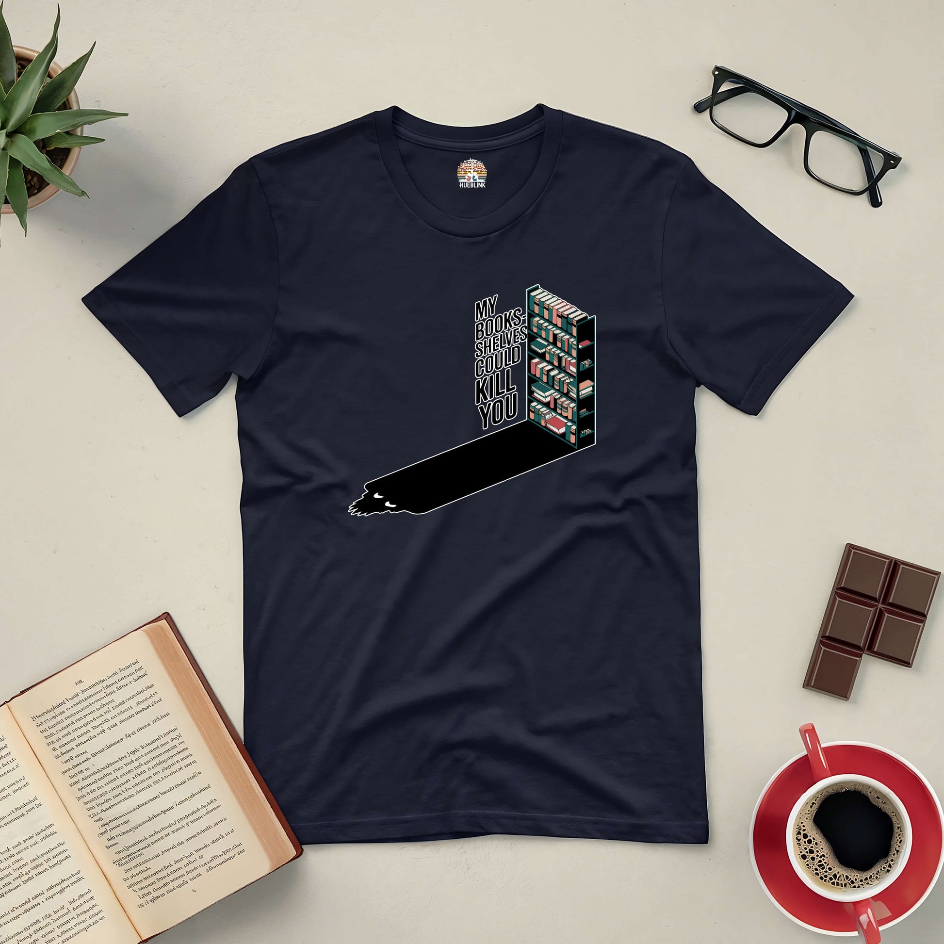 "My Bookshelves Could Kill You tee for book lovers, featuring a humorous bookshelf design, surrounded by coffee, books, and glasses."