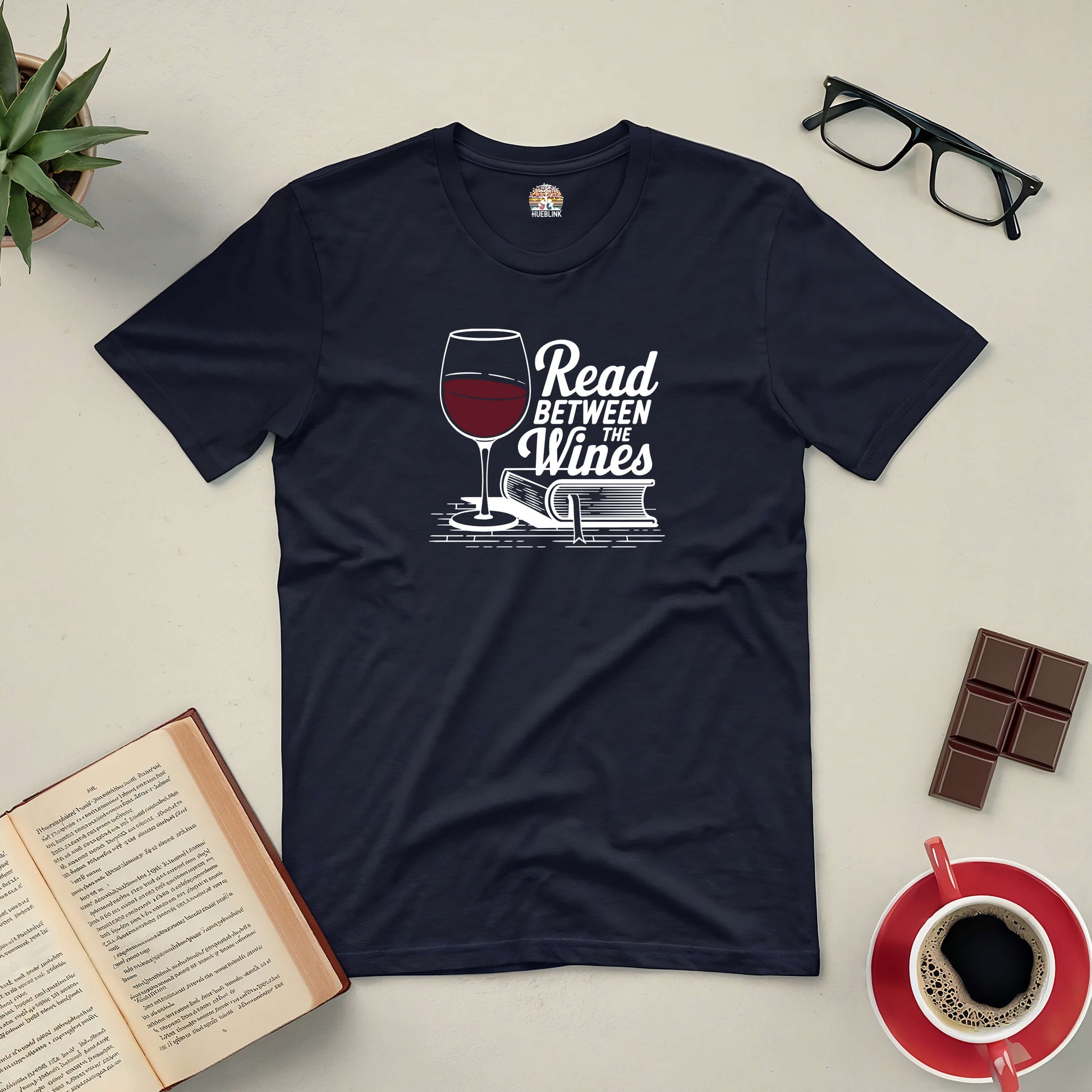 "Read Between the Wines Tee with book and wine design, perfect for book lovers and wine enthusiasts."