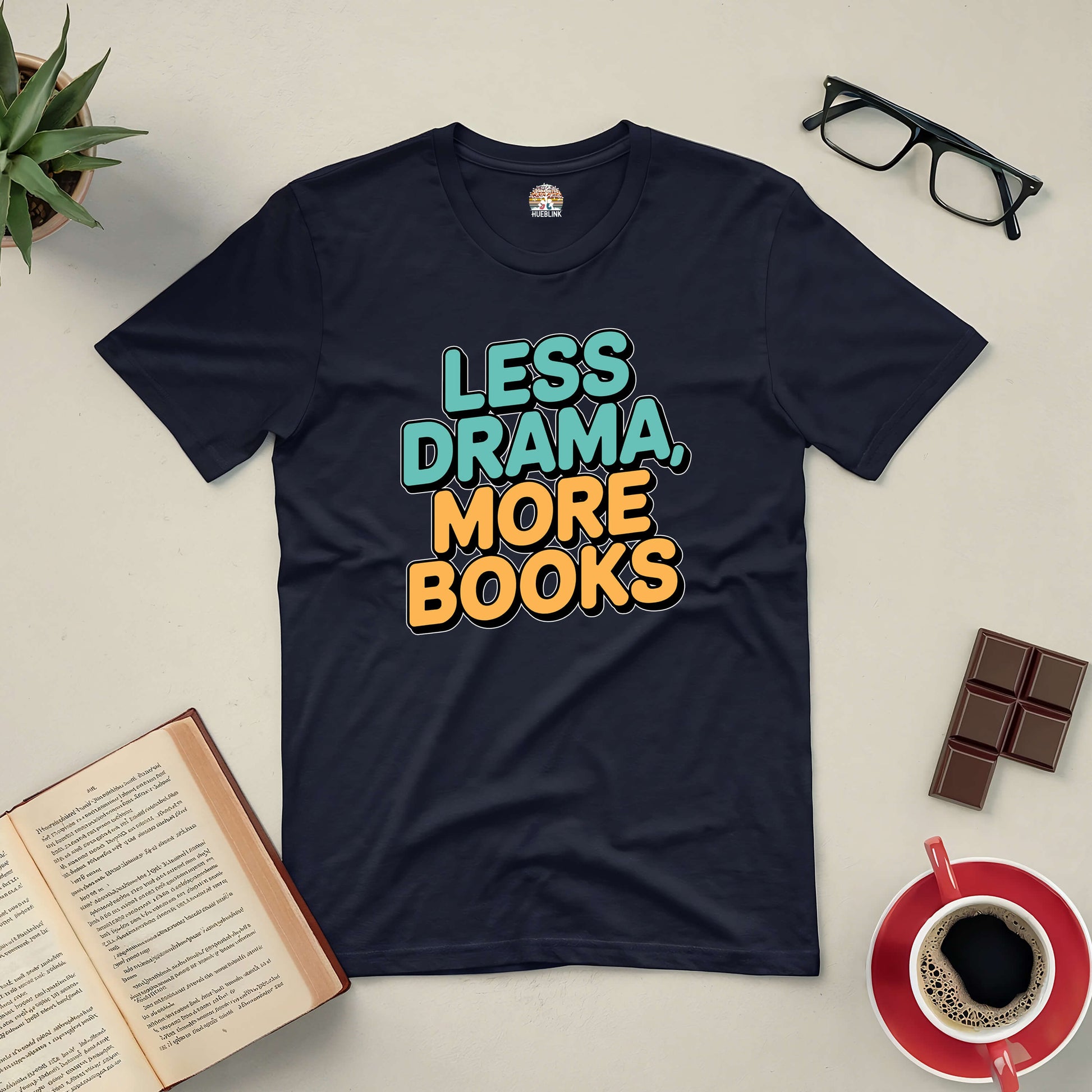 "Less Drama More Books tee on table with open book, glasses, chocolate, and coffee for book lovers"