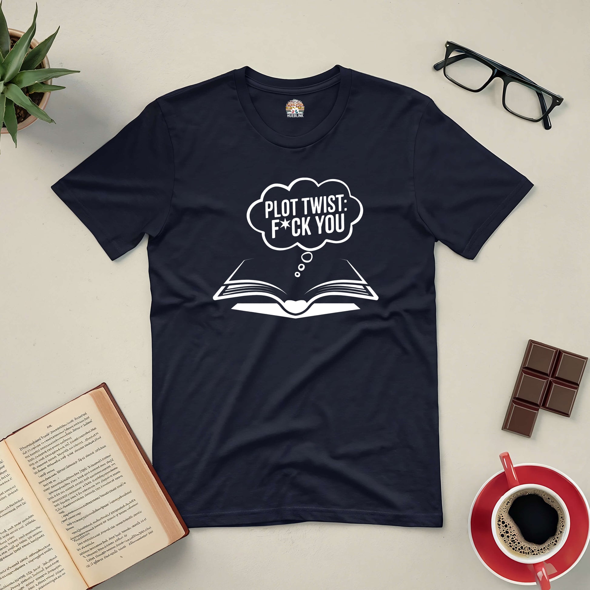 Black "Plot Twist: F*ck You" T-shirt for book lovers with humor, surrounded by books, glasses, chocolate, and a coffee cup.