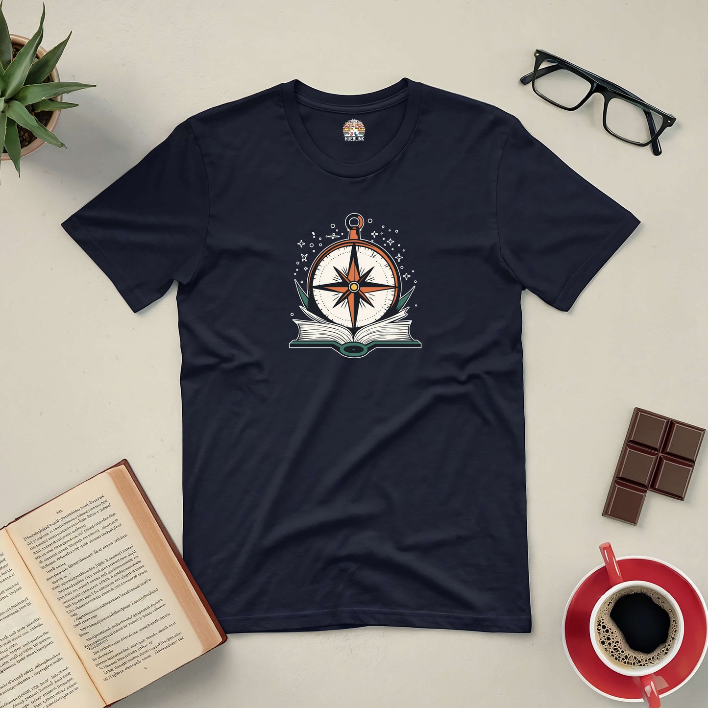 "Getting Back On Track Tee with compass and open book design, inspiring self-discovery through stories, surrounded by books and coffee"