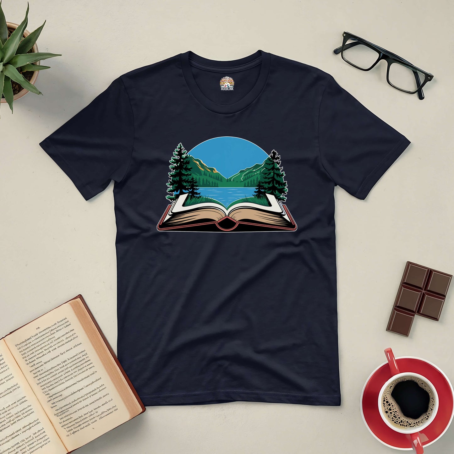 "Book Your Escape Tee with mountain and book graphic, ideal for nature lovers and book enthusiasts, surrounded by coffee and reading items"