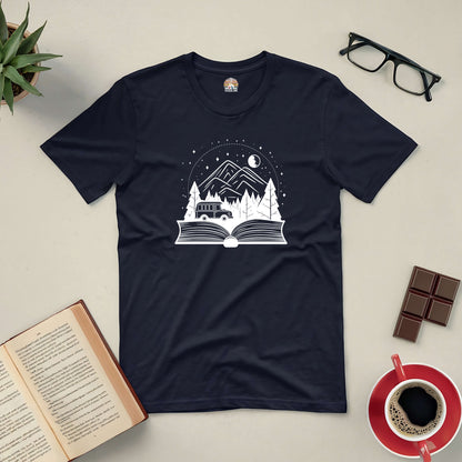 Black tee featuring an open book with a mountain and forest design, surrounded by a coffee cup, chocolate, glasses, and an open book.