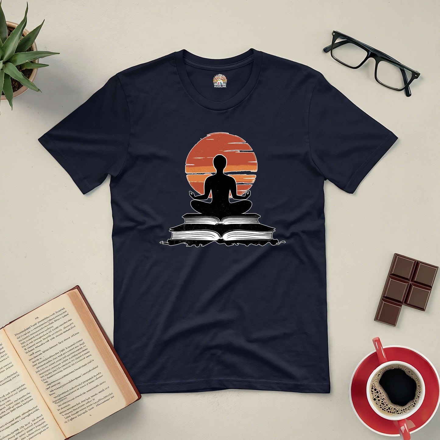 "Connection Established Tee with meditative book design, surrounded by open book, coffee, glasses, and chocolate on table"