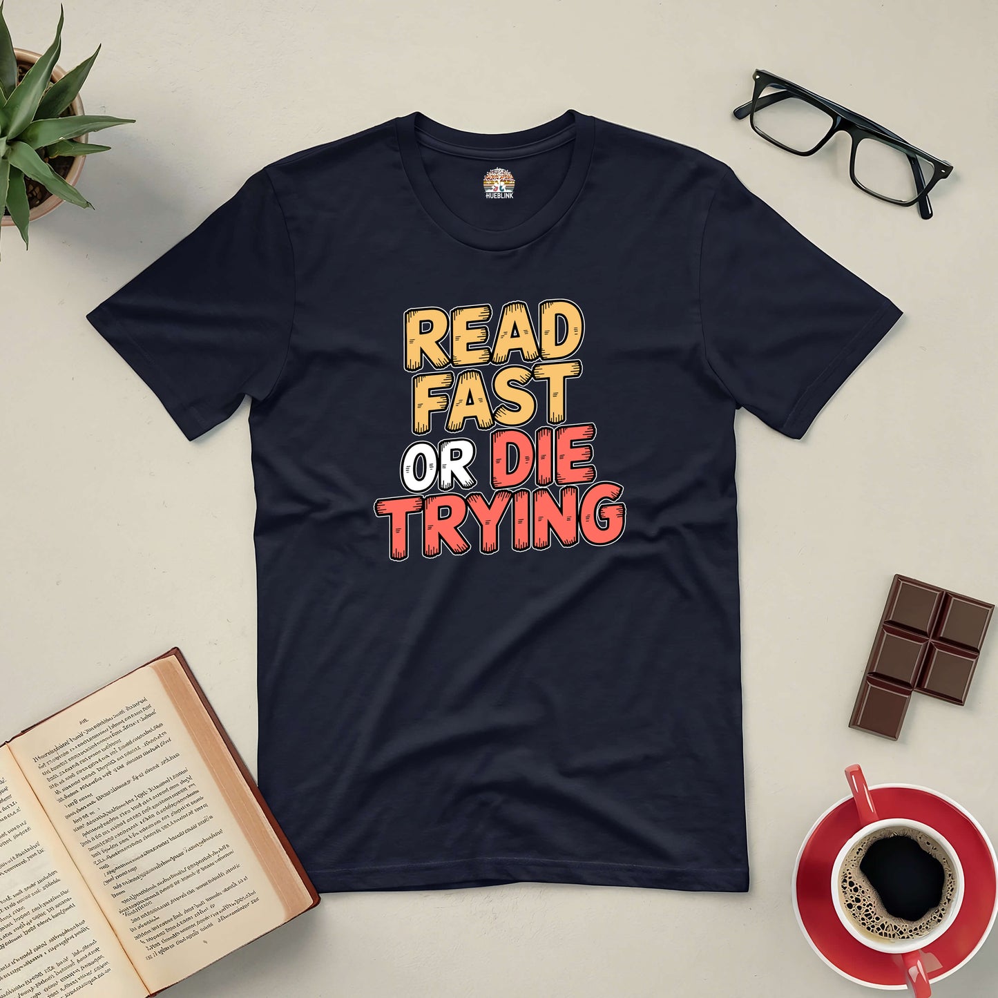 "Read Fast or Die Trying Tee with book, glasses, coffee, and chocolate on table for passionate readers"