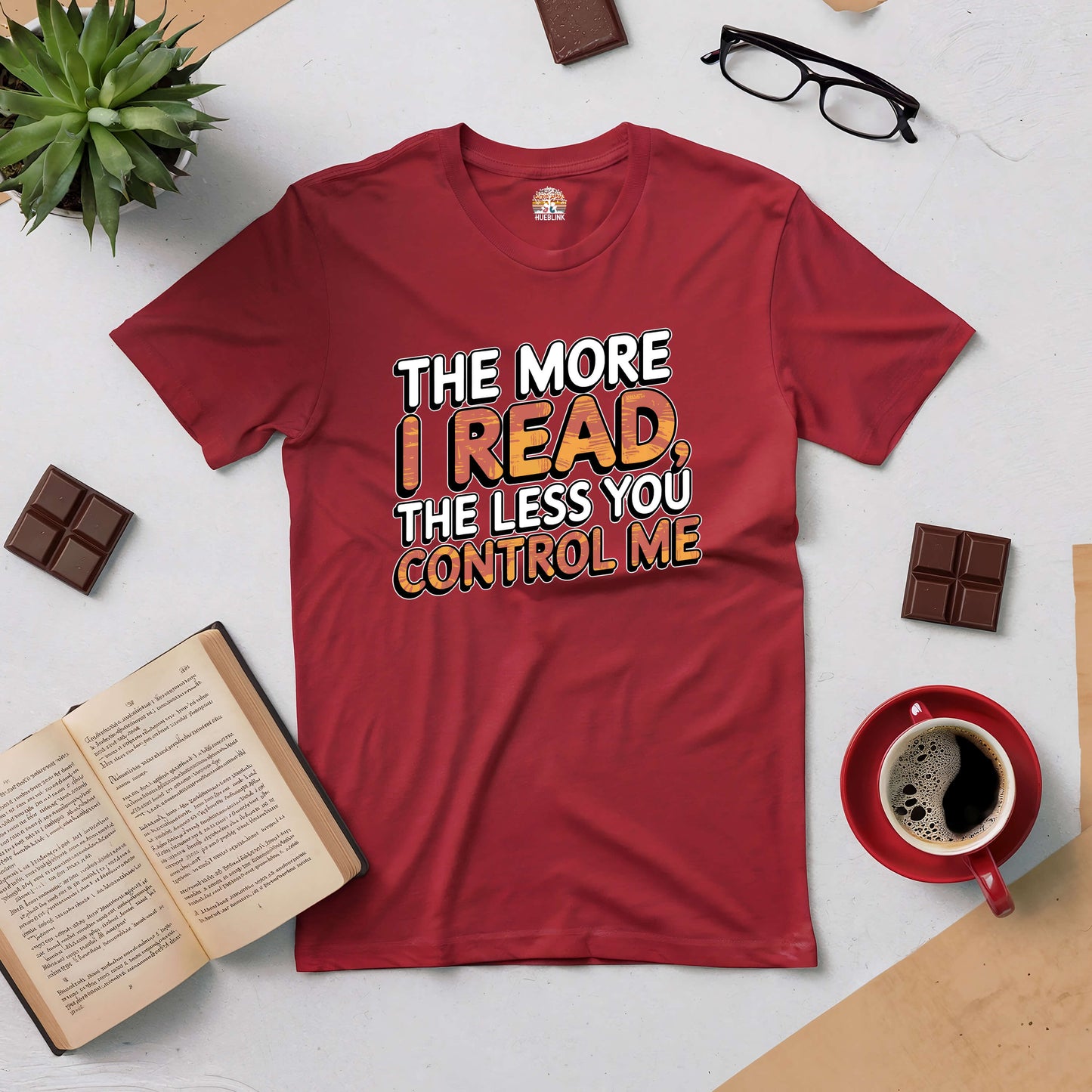 Red tee with "The More I Read, The Less You Control Me" print, surrounded by books, coffee, and glasses.