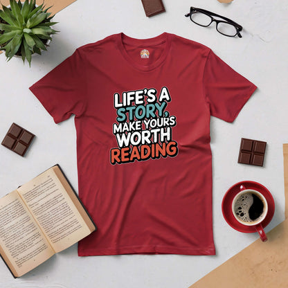 Red tee with "Life's a Story, Make Yours Worth Reading" text, surrounded by books, glasses, chocolate, and coffee.