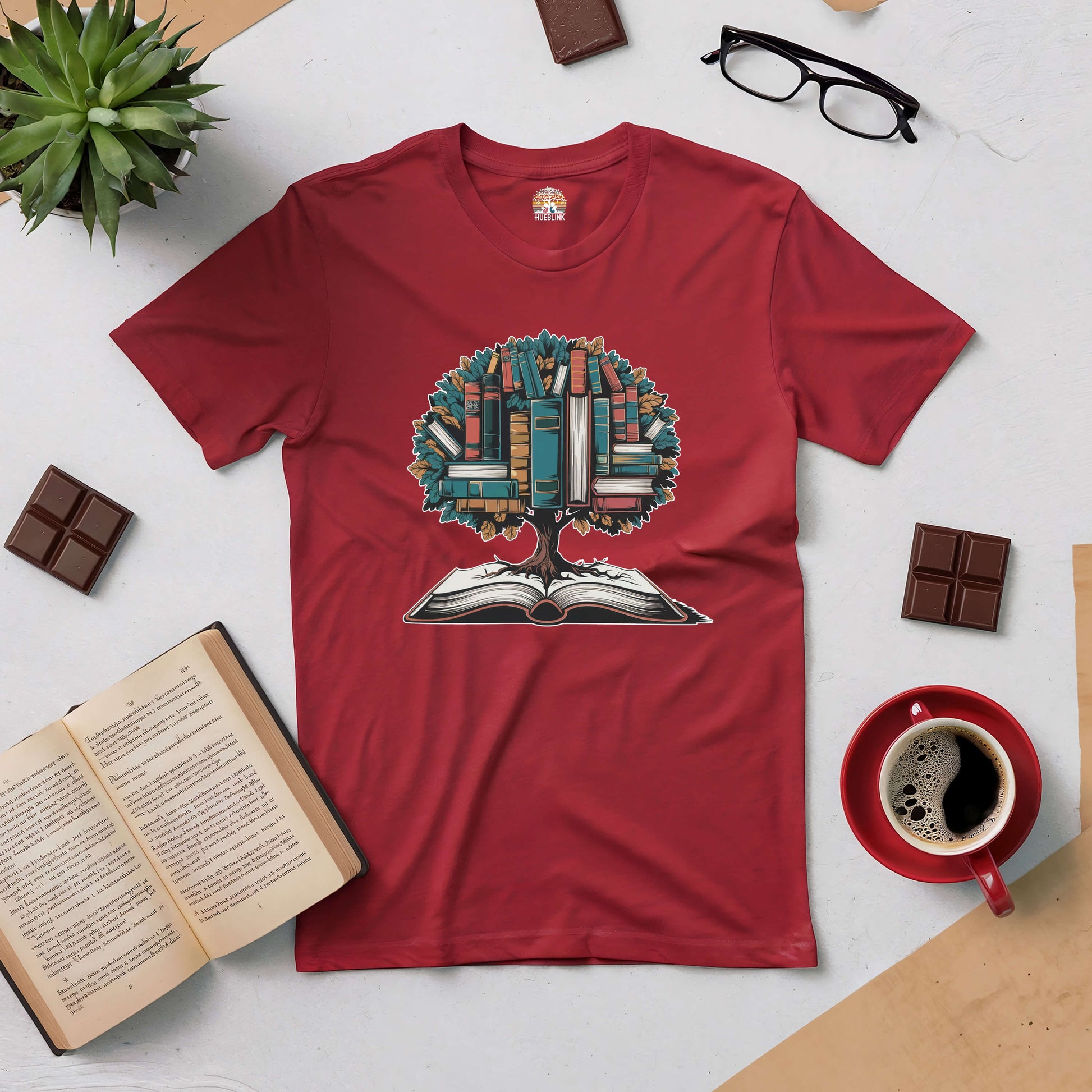 Red T-shirt featuring a tree blossoming with books, surrounded by coffee, glasses, chocolate, and an open book.