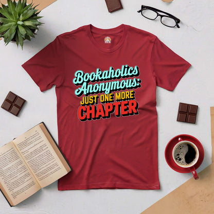 Red Bookaholics Anonymous tee with "Just One More Chapter" slogan, surrounded by open book, glasses, and a cup of coffee.