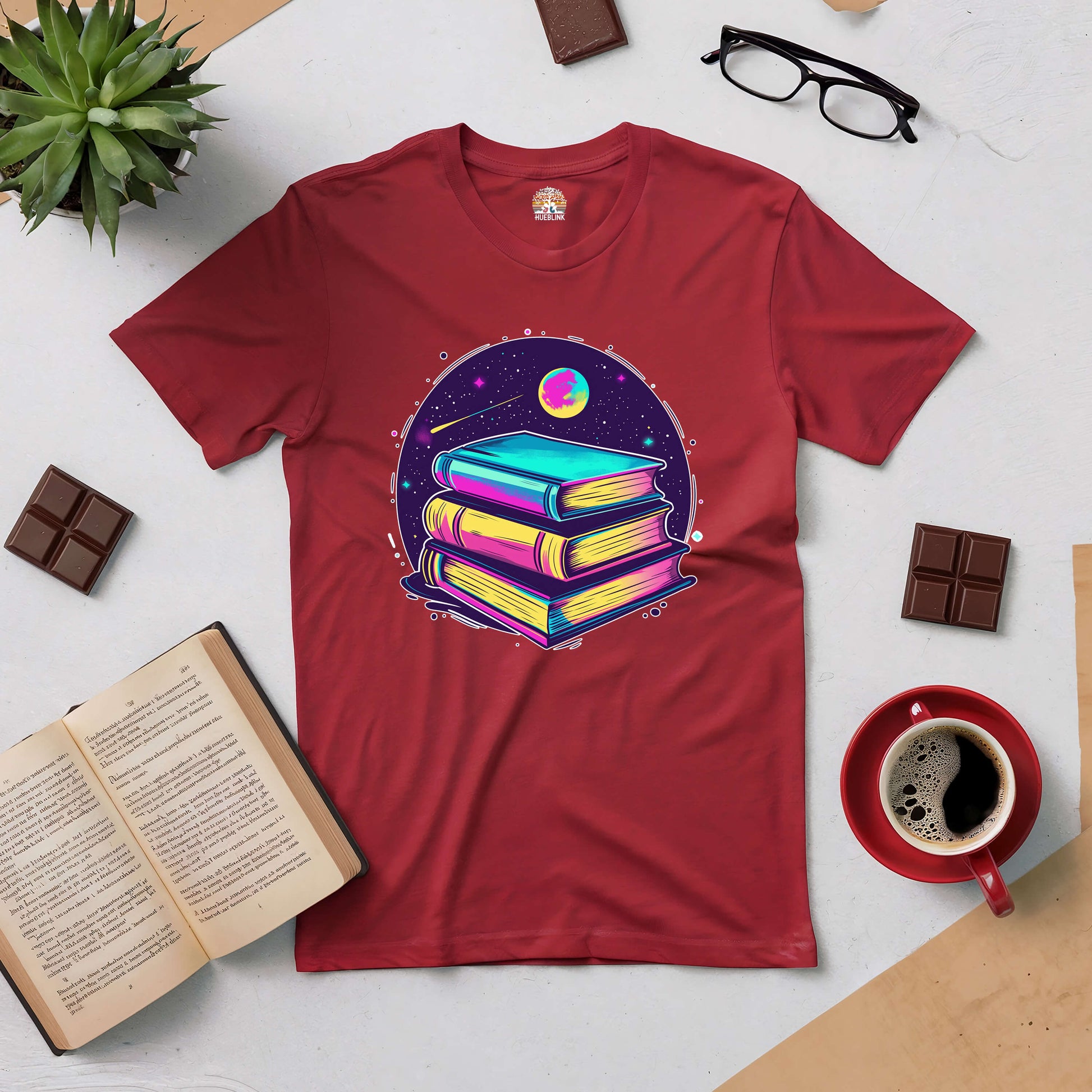 "Red tee with colorful stack of books surrounded by planets, symbolizing books as portals to infinite universes."