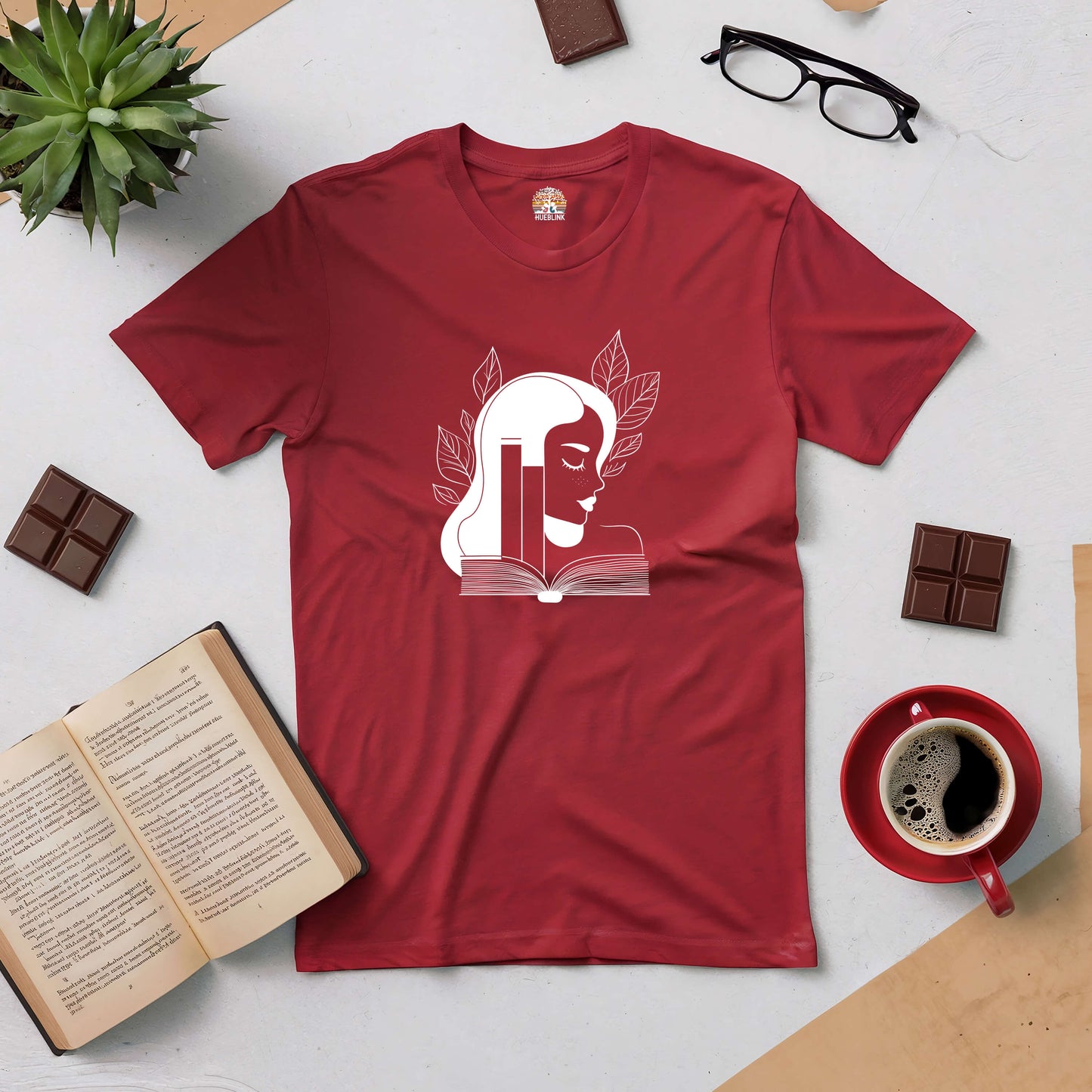 "Beauty in Every Page Tee featuring elegant book-themed design, perfect for book lovers, shown with books, coffee, and chocolate."