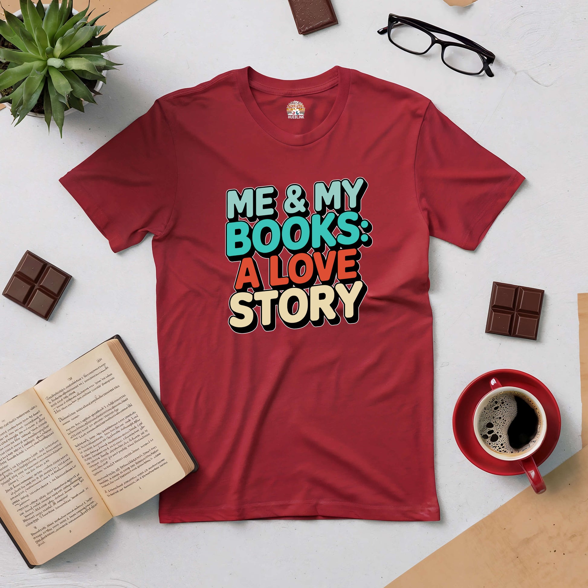 Red "Me & My Books: A Love Story" tee surrounded by books, chocolate, coffee, and glasses for book lovers.