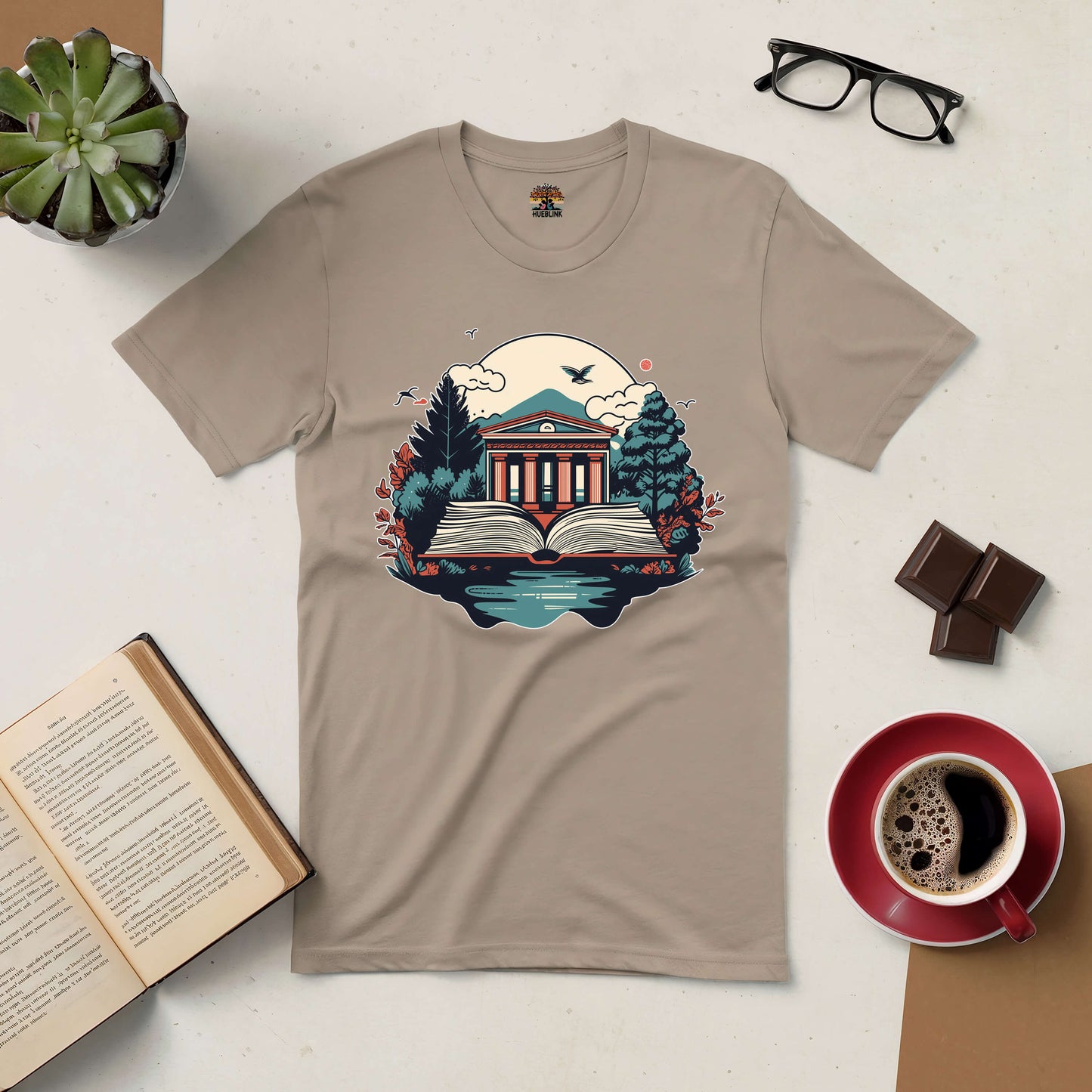 Beige t-shirt featuring a library and nature design symbolizing the gateway to knowledge, surrounded by book, coffee, and glasses.