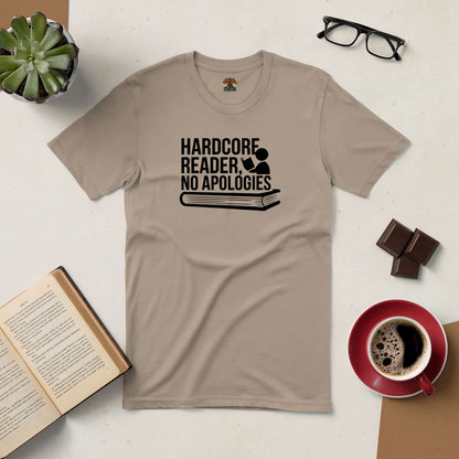 Beige "Hardcore Reader, No Apologies" t-shirt surrounded by open book, coffee cup, glasses, chocolates, and a plant.