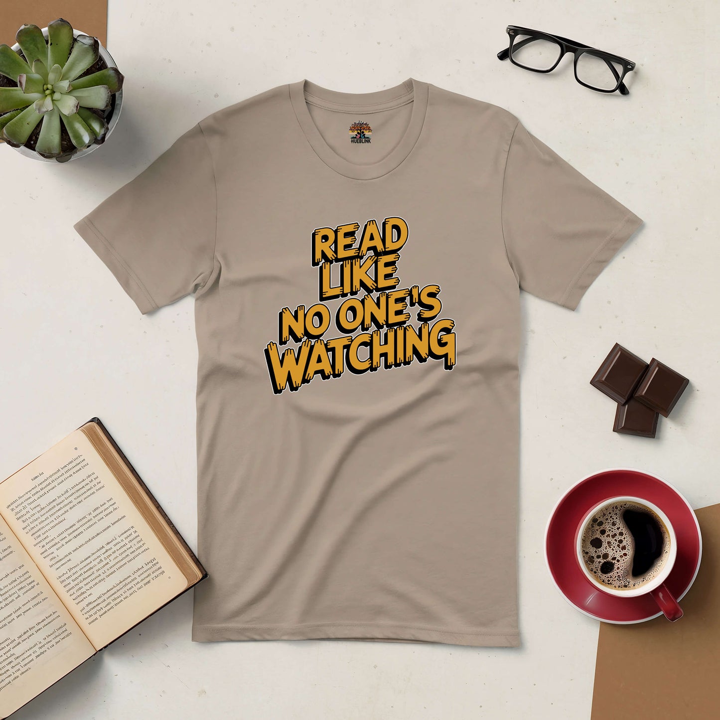 "Read Like No One's Watching Tee with books, coffee, and glasses on a table"