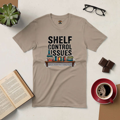 Shelf Control Issues tee with books graphic, surrounded by coffee, chocolate, and open book on a table.